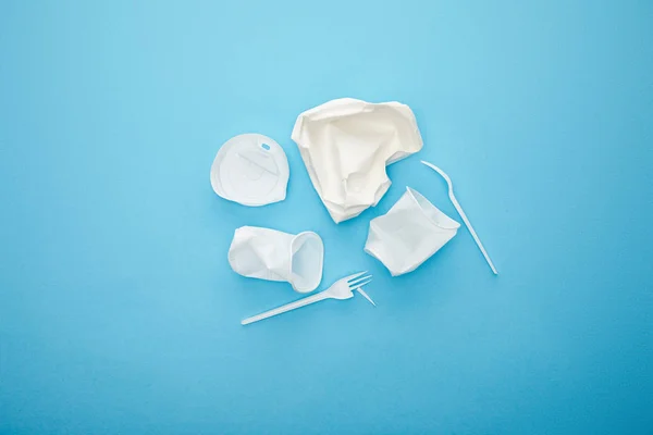 Top view of pile of white disposable cups, forks and plate on blue background — Stock Photo