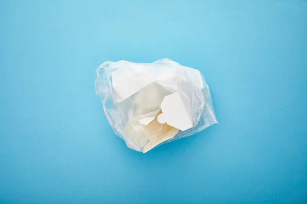 Top view of plastic bag with disposable cardboard containers on blue background — Stock Photo