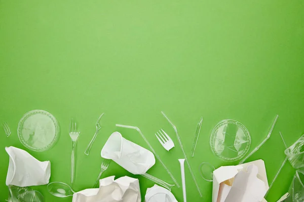 Вид зверху на одноразові пластикові чашки, вилки, ложки та картонні контейнери на зеленому фоні з місцем для тексту — стокове фото