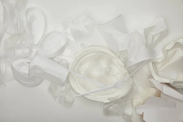 Top view of crumpled plastic cups, plates and cardboard container on white background — Stock Photo