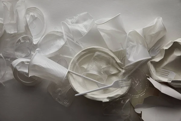 Top view of crumpled plastic cups, plates and cardboard container on white background  with shadow — Stock Photo