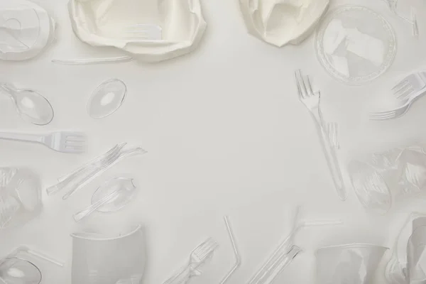 Vue du dessus des tasses, fourchettes, cuillères et assiettes froissées jetables sur fond blanc avec espace de copie — Photo de stock