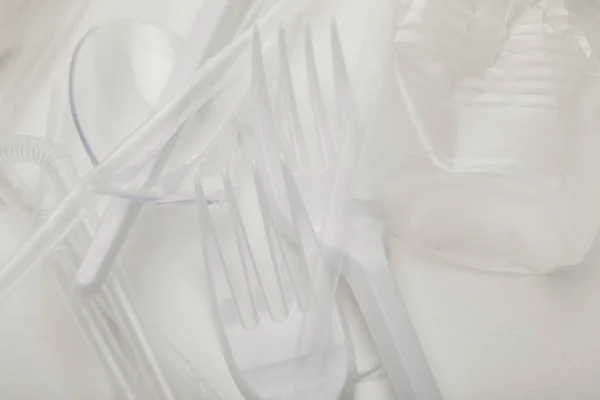 Close up view of crumpled plastic cup, forks and spoons on white background — Stock Photo