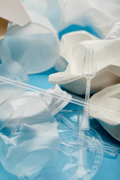 Haufen zerknüllter Plastikbecher auf blauem Hintergrund — Stockfoto