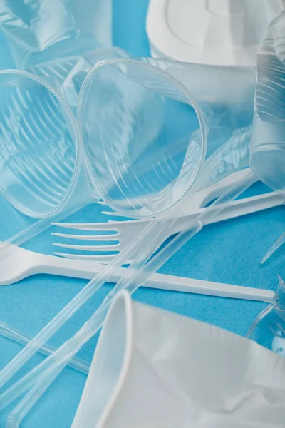 Pile de gobelets et fourchettes en plastique froissé sur fond bleu — Photo de stock