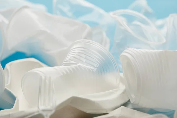 Vue rapprochée de la pile de gobelets en plastique transparent et blanc sur fond bleu — Photo de stock