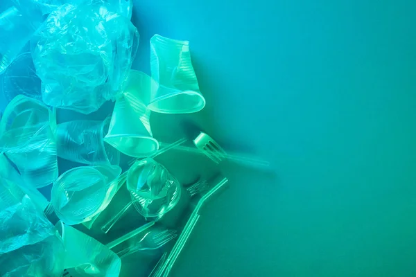 Vista dall'alto di sacchetti di plastica spiegazzati, tazze, cannucce e forchette con spazio copia in luce blu — Foto stock