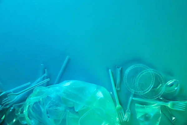 Vista superior de sacos de plástico amassados, copos e lixo de papelão com espaço de cópia em luz azul — Fotografia de Stock