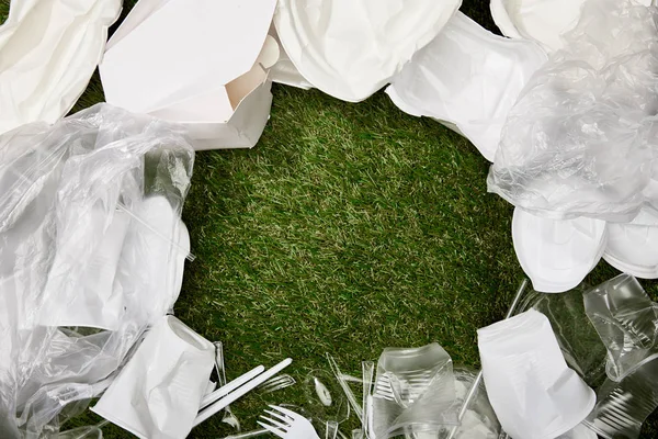 Vista dall'alto di sacchetti di plastica accartocciati, tazze e rifiuti di cartone sull'erba con spazio per la copia — Foto stock