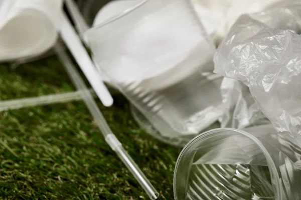 Vista da vicino di bicchieri di plastica accartocciati e sacchetti sull'erba — Foto stock