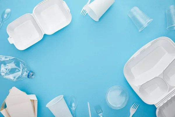 Top view of plastic and cardboard disposable rubbish on blue background with copy space — Stock Photo