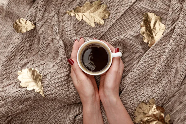 Partial view of woman holding mug with coffee on knitted brown sweater with golden leaves — Stock Photo