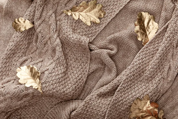 Top view of golden foliage scattered on knitted brown sweater — Stock Photo