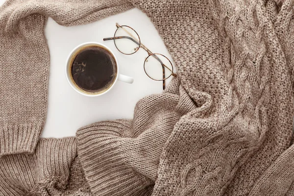 Draufsicht auf gestrickten braunen Pullover, Kaffee und Gläser auf weißem Hintergrund — Stockfoto