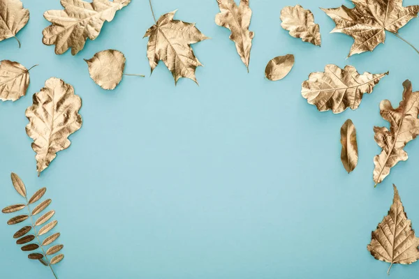 Vue de dessus des feuilles dorées automnales sur fond bleu — Photo de stock