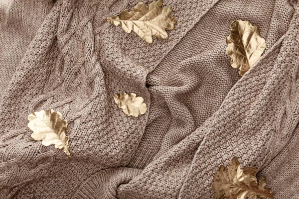 Top view of knitted brown sweater with golden painted leaves — Stock Photo