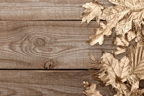 Top view of golden foliage on wooden textured background — Stock Photo