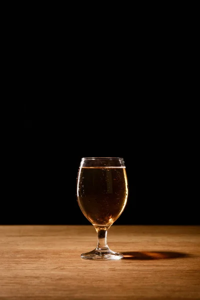 Vaso de cerveza fresca sobre mesa de madera aislada sobre negro - foto de stock