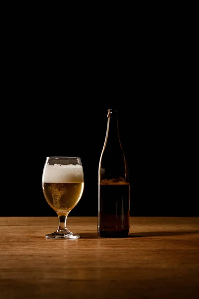 Bier in Flasche und Glas auf Holztisch isoliert auf schwarz — Stockfoto
