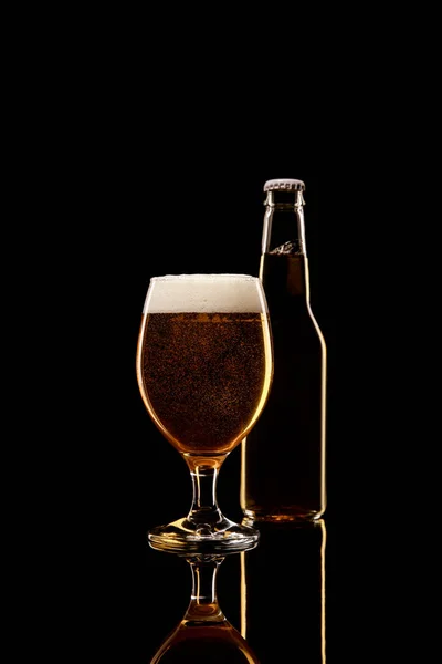 Flasche und Glas Bier mit weißem Schaum isoliert auf schwarz — Stockfoto