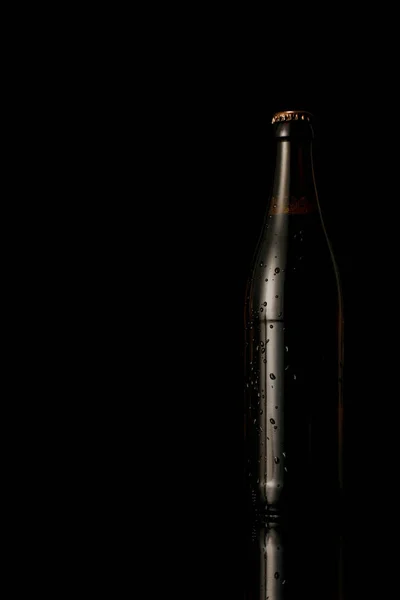 Botella de vidrio de cerveza con gotas de agua aisladas en negro - foto de stock