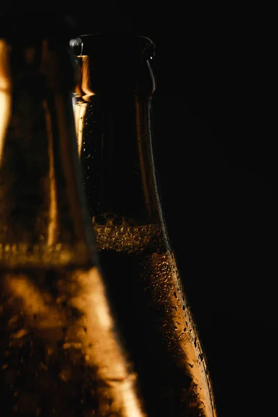 Крупним планом вид скляних пляшок пива з краплями води і бульбашками ізольовані на чорному — стокове фото