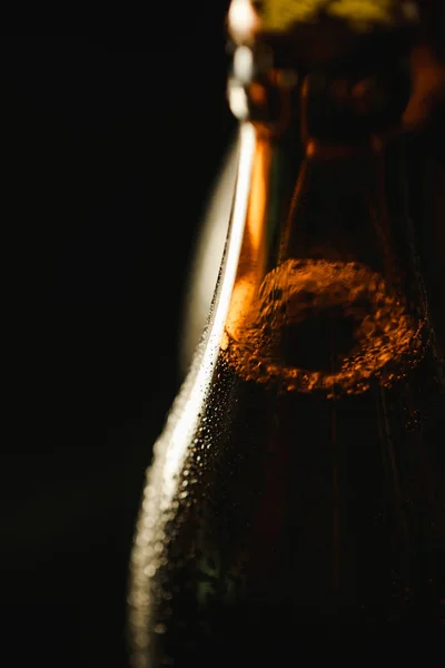 Nahaufnahme der nassen Flasche Bier mit Blasen isoliert auf schwarz — Stockfoto