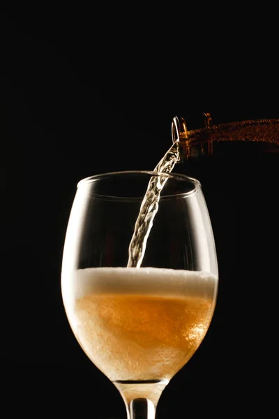 Goldenes Bier, das aus der Flasche ins Glas fließt, isoliert auf schwarz — Stockfoto