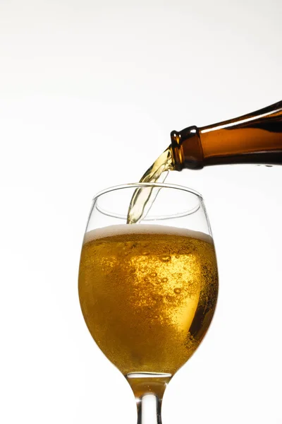Низький кут зору свіжого пива, що ллється з пляшки в склянку ізольовано на білому — стокове фото
