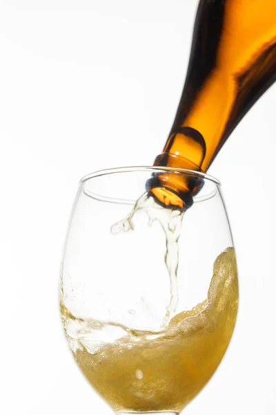 Birra versata dalla bottiglia al bicchiere con spruzzata isolata sul bianco — Foto stock