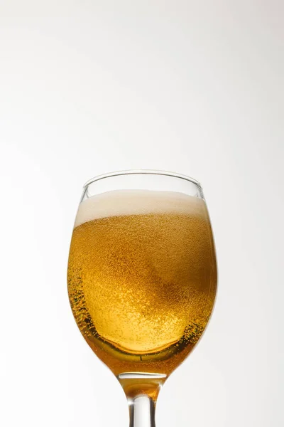 Vista en ángulo bajo del vaso de cerveza con espuma aislada en blanco - foto de stock