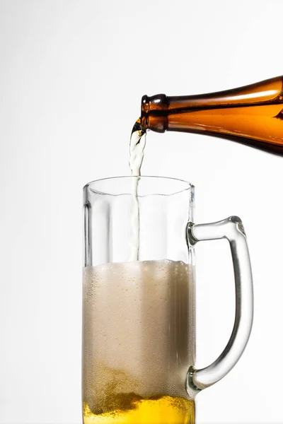 Beer pouring from bottle into glass with foam isolated on white — Stock Photo
