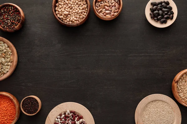 Ansicht von Hülsenfrüchten und Getreide in Schalen auf dunkler Holzoberfläche mit Kopierraum — Stockfoto
