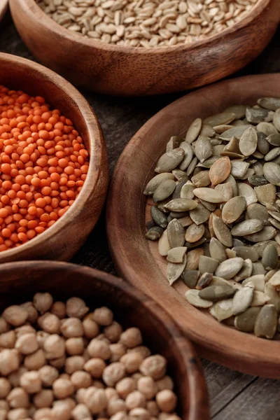 Close up view of wooden bowls with chickpea, lentil, oatmeal and pumpkin seeds — Stock Photo