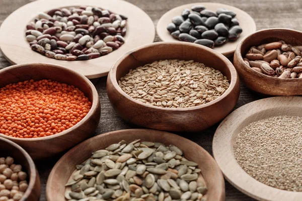 Tazones de madera con avena cruda, lentejas rojas, varios frijoles, quinua y semillas de calabaza - foto de stock