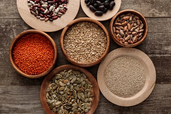 Ansicht von Holzschalen mit rohem Haferflocken, roter Linse, verschiedenen Bohnen, Quinoa und Kürbiskernen — Stockfoto