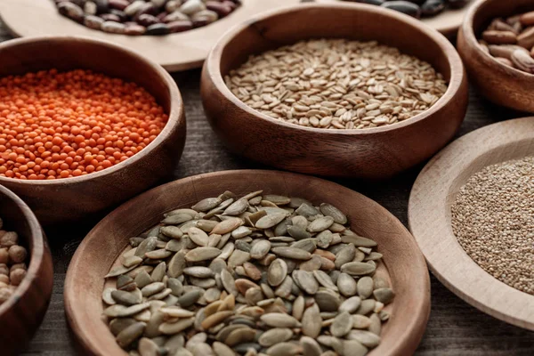 Wooden plates and bowls with raw red lentil, pumpkin seeds and oatmeal on table — Stock Photo