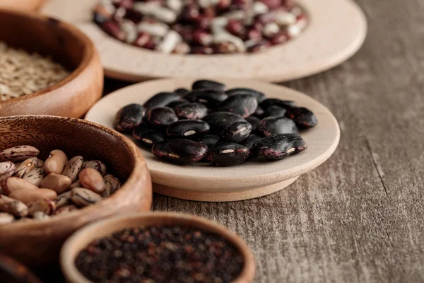 Ciotole e piatti marroni con fagioli neri e cereali sul tavolo — Foto stock