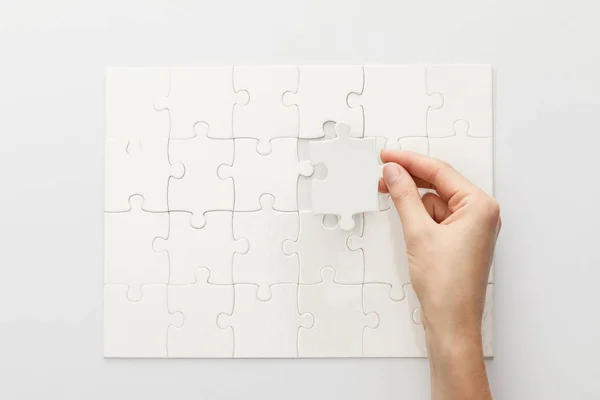 Abgeschnittene Ansicht einer Frau, die Puzzle auf weißem Hintergrund vervollständigt — Stockfoto
