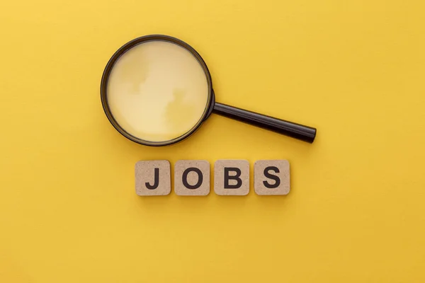 Ansicht der Lupe in der Nähe von Kartonquadraten mit Jobs-Schriftzug auf gelbem Hintergrund — Stockfoto