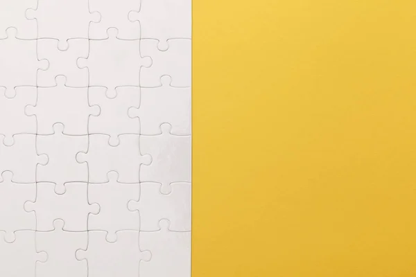 Vue du haut du puzzle blanc terminé sur fond jaune — Photo de stock