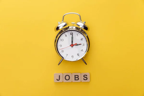 Draufsicht auf Uhr und Kartonquadrate mit Jobs-Inschrift auf gelbem Hintergrund — Stockfoto