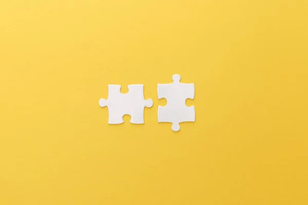 Top view of white puzzle pieces on yellow background — Stock Photo