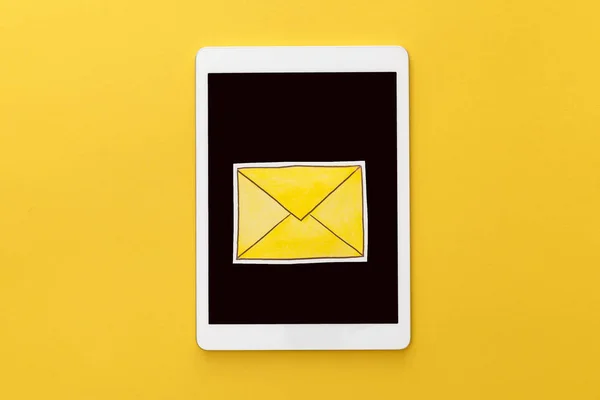 Верхний вид буквы на цифровом планшете с пустым экраном на желтом фоне — стоковое фото