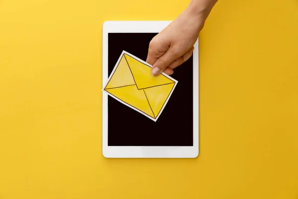 Cropped view of woman holding letter under digital tablet with blank screen on yellow background — Stock Photo