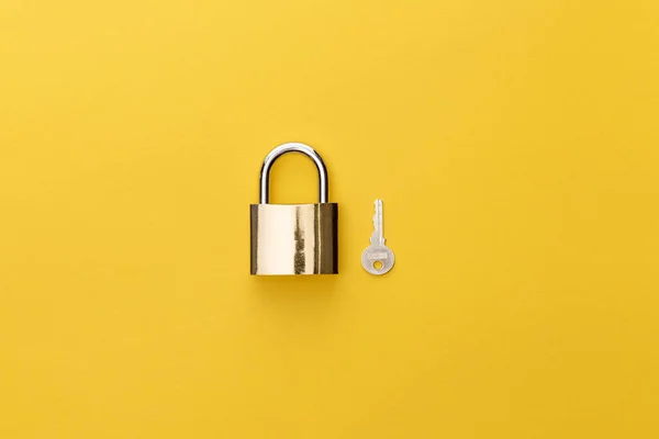 Top view of padlock near key on yellow background — Stock Photo