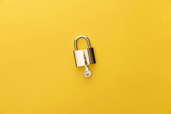 Vue du haut de la clé dans le cadenas sur fond jaune — Photo de stock