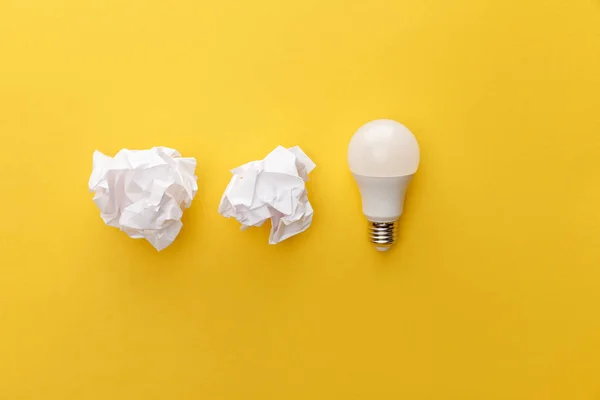 Top view of crumpled paper near light bulb on yellow background — Stock Photo