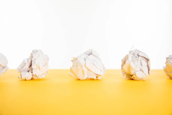 Crumpled paper on yellow surface isolated on white — Stock Photo