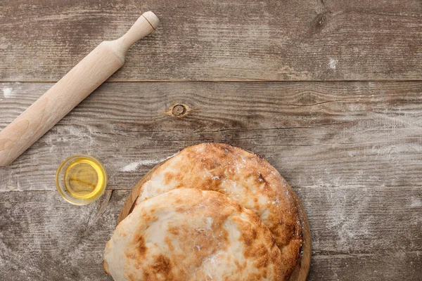 Vue du dessus du pain de lavande près de la tasse d'huile d'olive et rouleau à pâtisserie sur la table en bois — Photo de stock